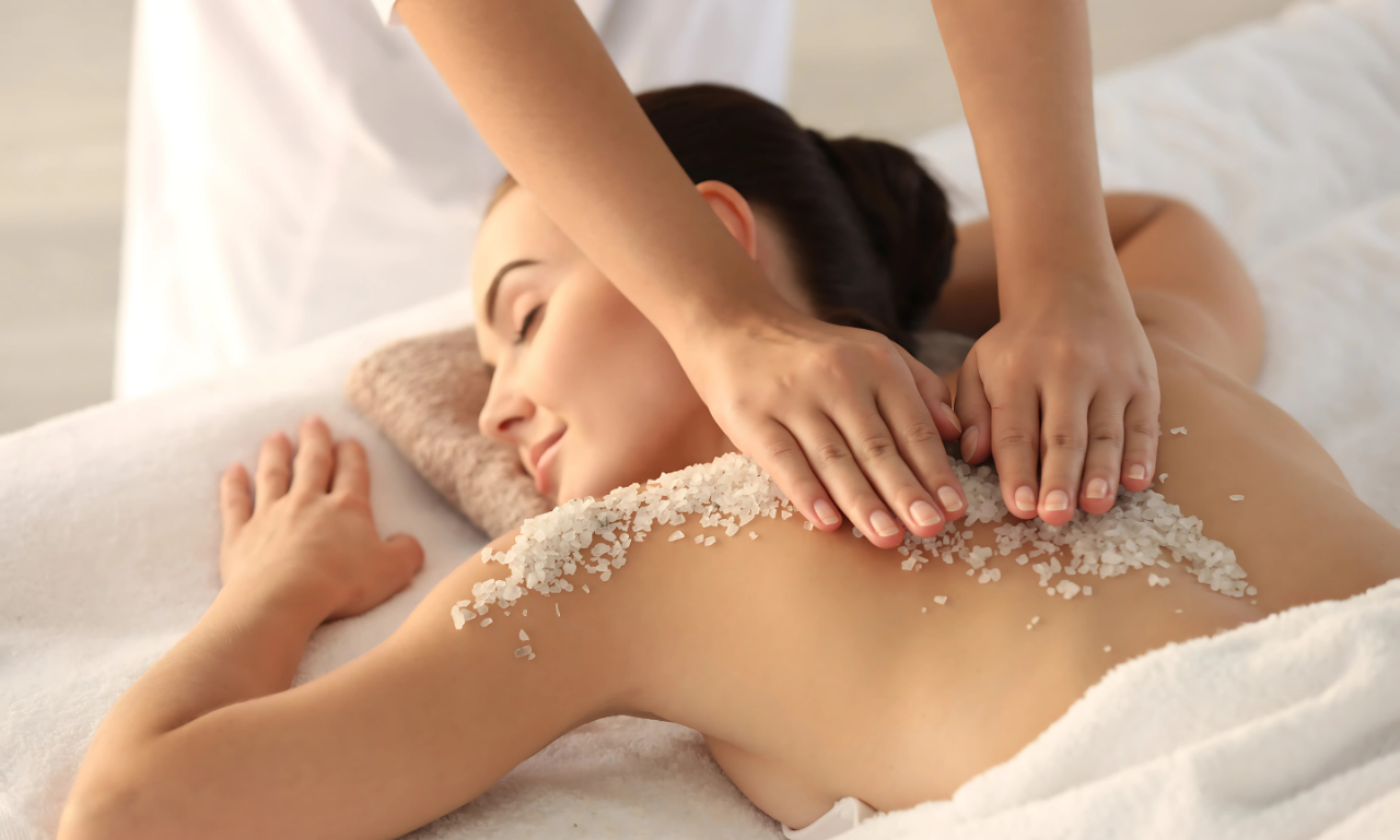 scrubn Woman receiving salt scrub back massage at spa