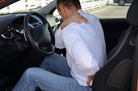 Man sitting in car holding neck in pain
