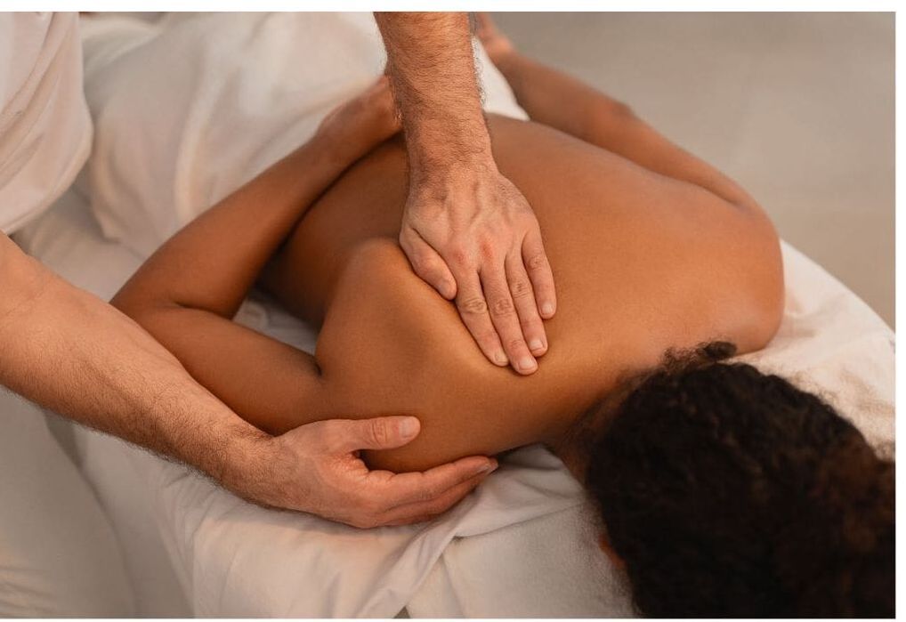 Person receiving shoulder massage on massage table