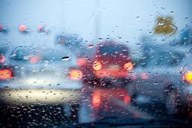 Blurred traffic seen through rain-covered windshield